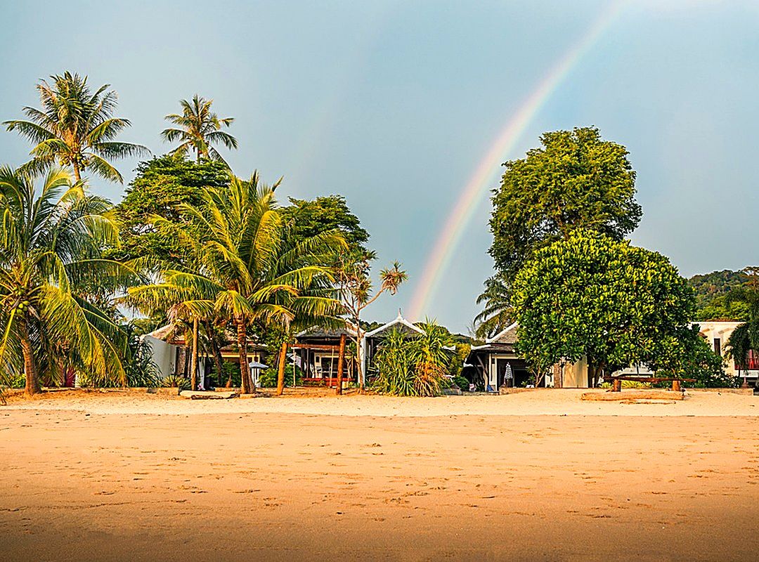 Rainbow over the beach villas — showers clear, sky opens
